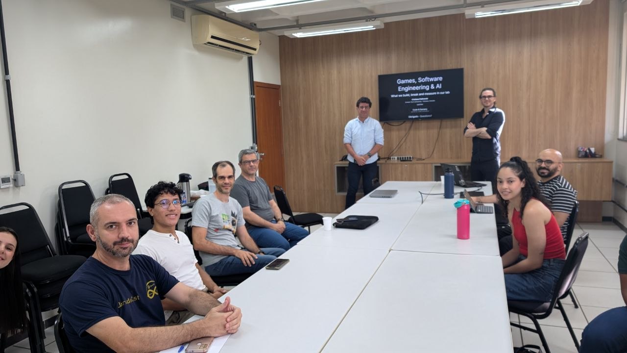 Seminar room at DCC/UFMG with attendees seated around a table and the title slide on screen